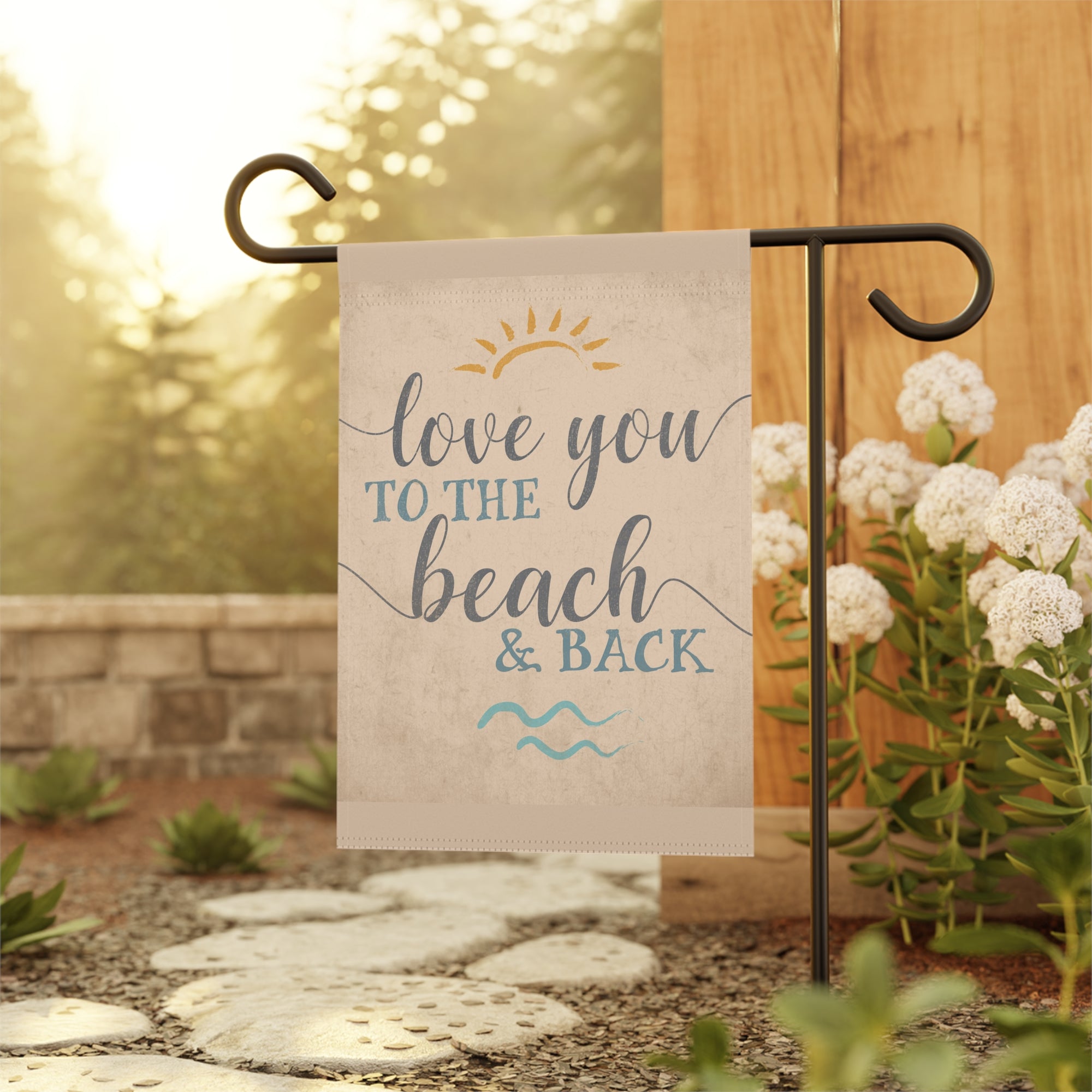 Coastal love garden flag displayed outdoors on a flag stand at a beach house