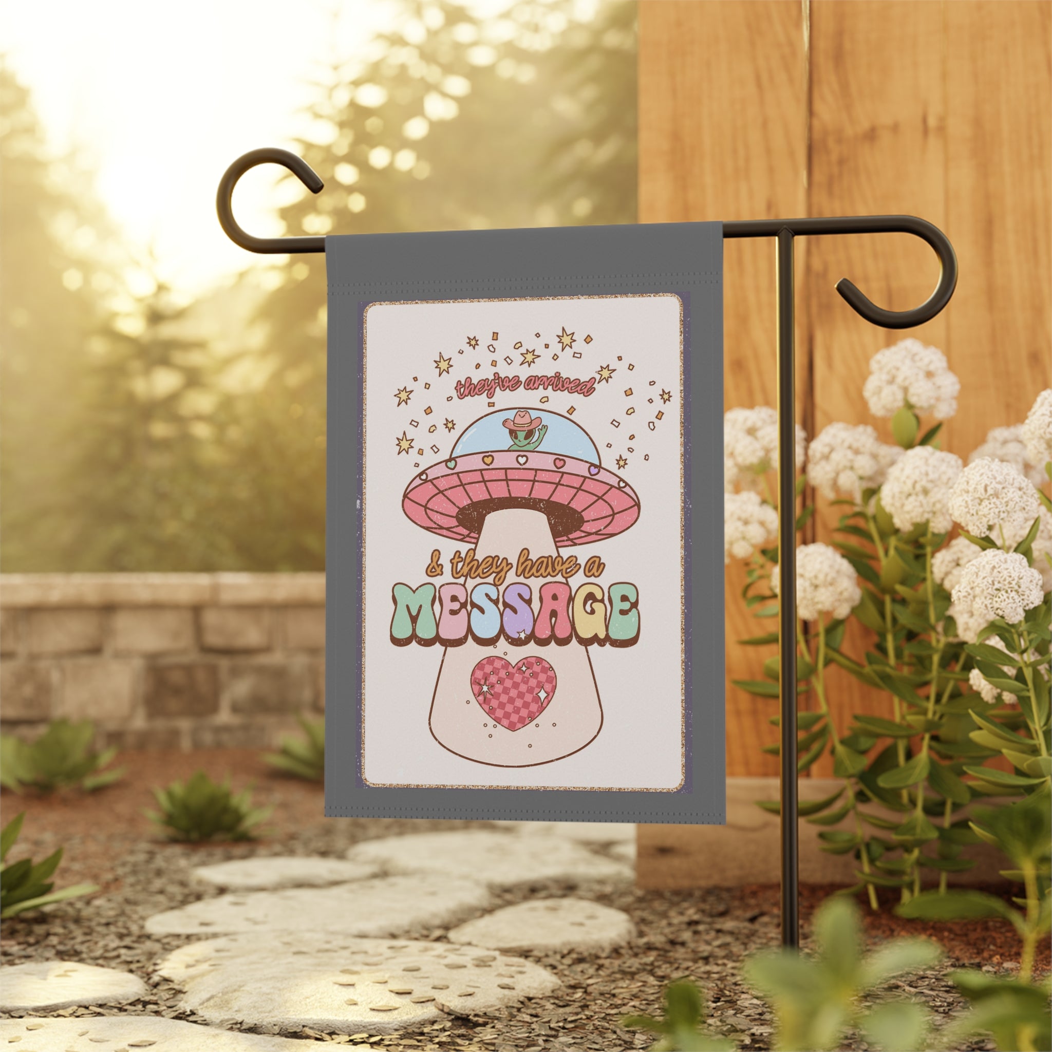 Quirky cowboy alien garden flag displayed outdoors on a porch flag stand