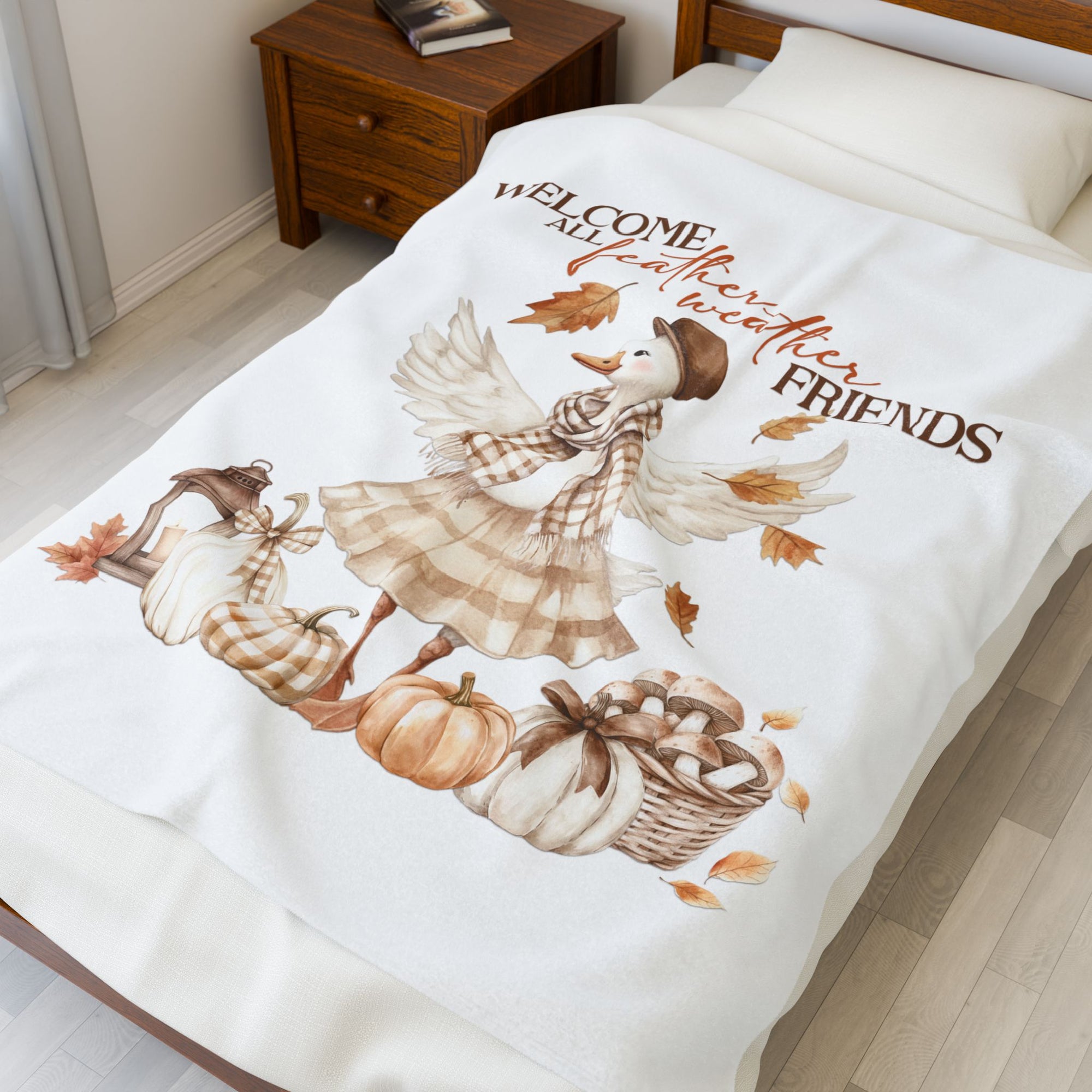 Decorative blanket with autumn-themed design featuring a goose, pumpkins, and text on a bed.