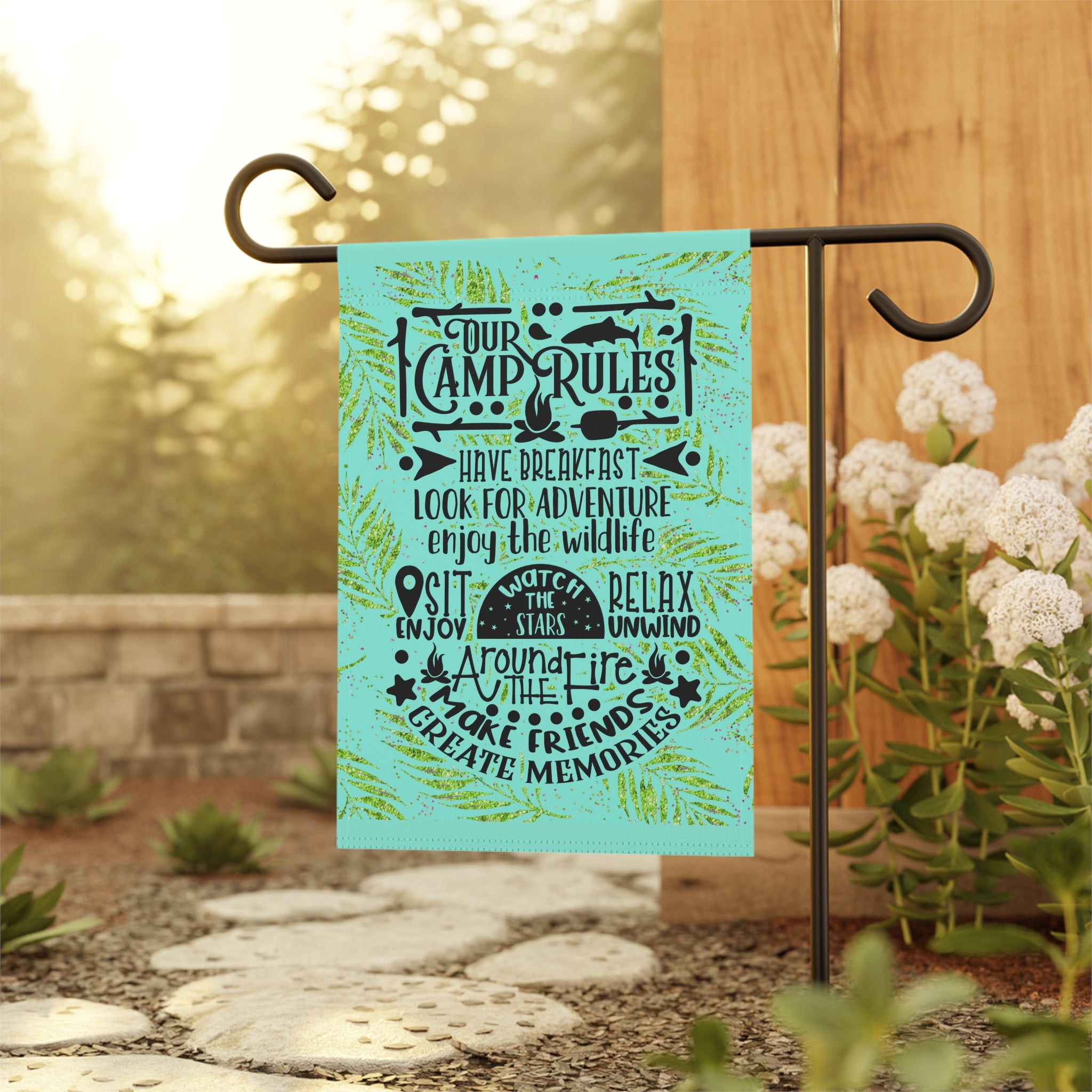 Funny camping garden flag displayed outdoors at a campsite fire pit