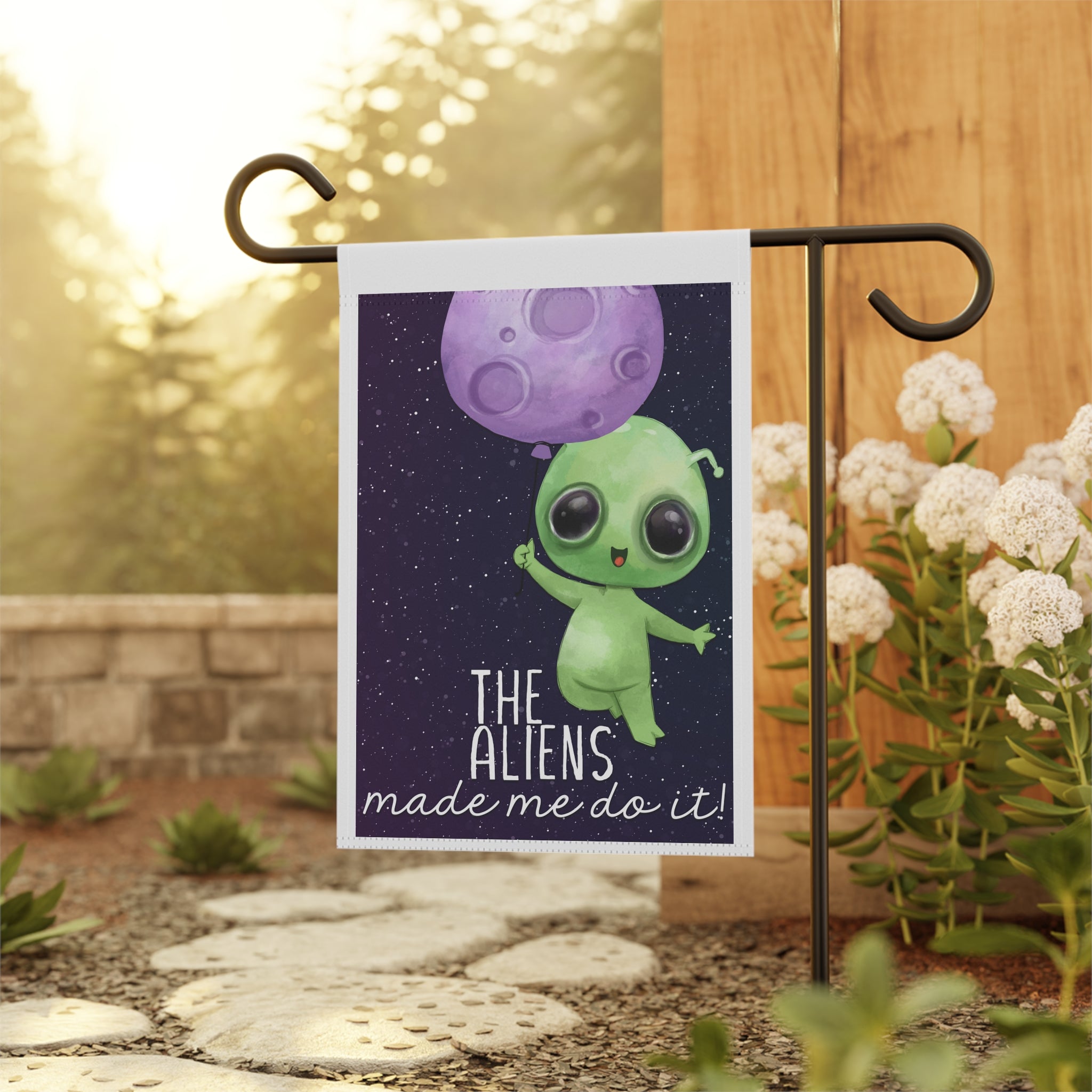 Funny alien garden flag displayed outdoors on a porch flag stand