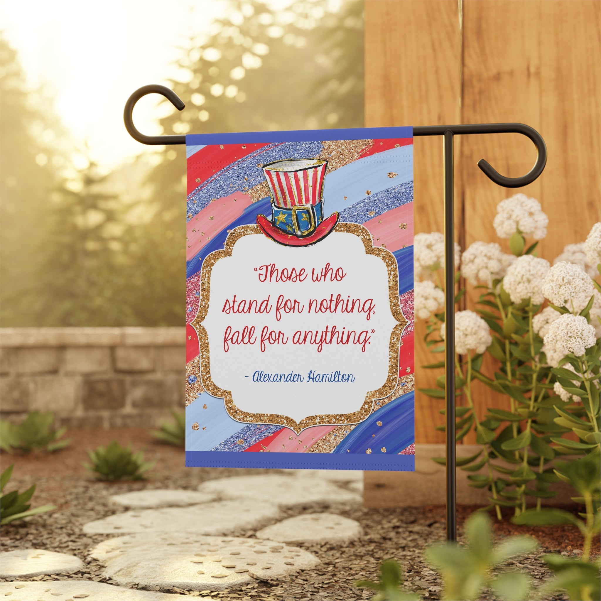 Patriotic Hamilton quote garden flag displayed outdoors on a metal flag stand
