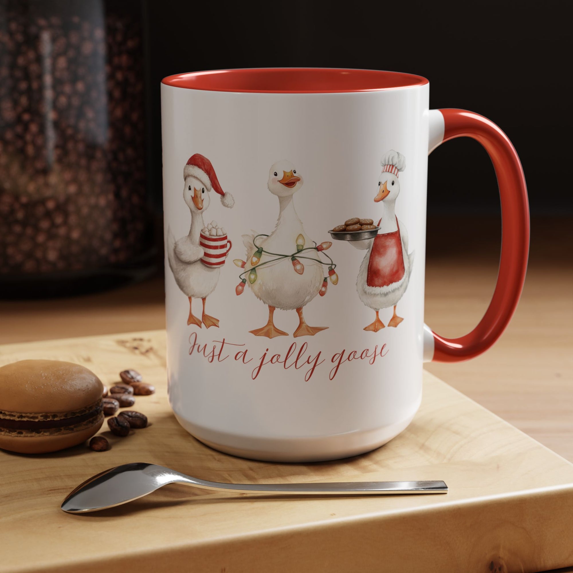 Mug with cartoon geese design and text on a wooden surface with coffee beans and a macaron.