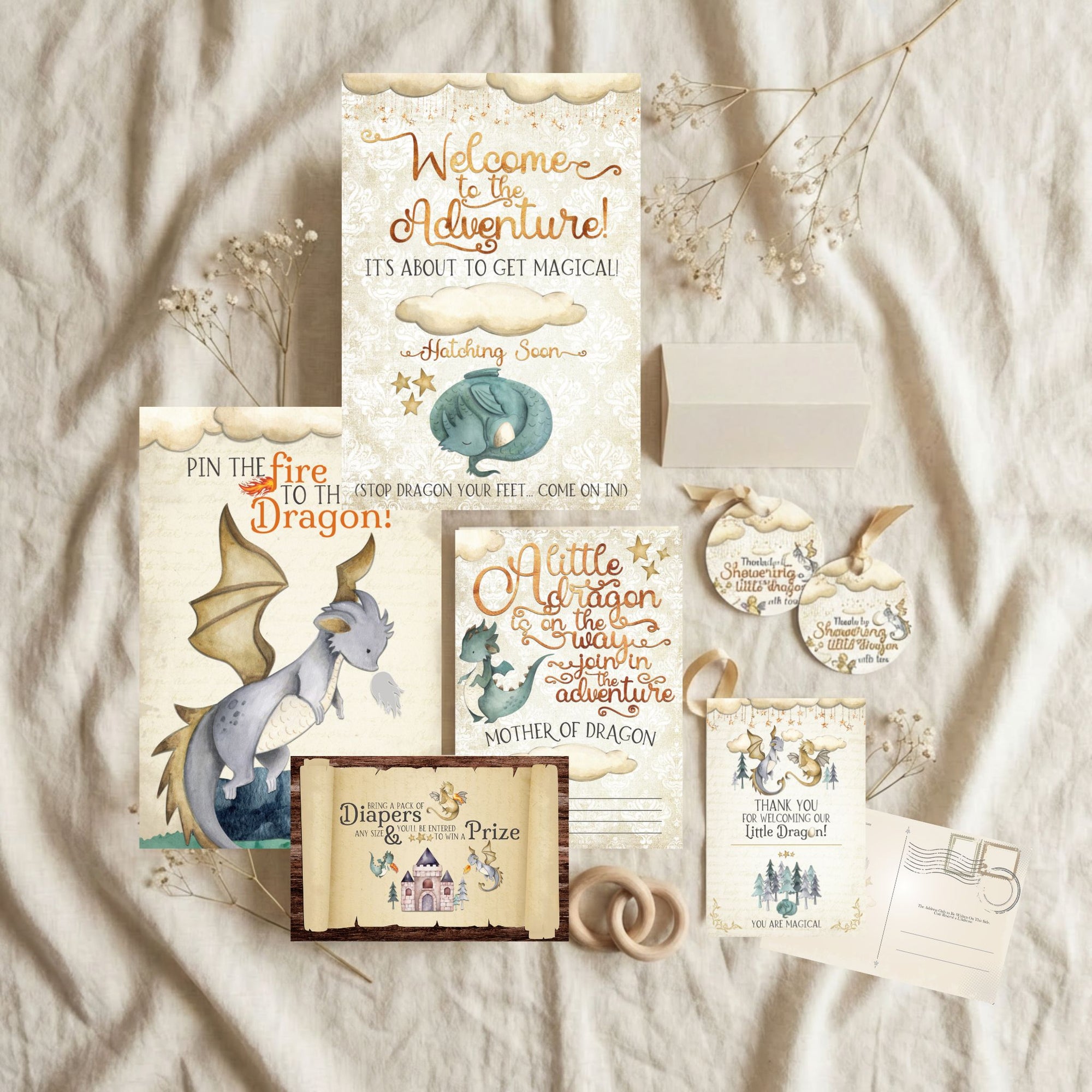 Collection of dragon-themed baby shower invitations and decorations on a textured fabric background.