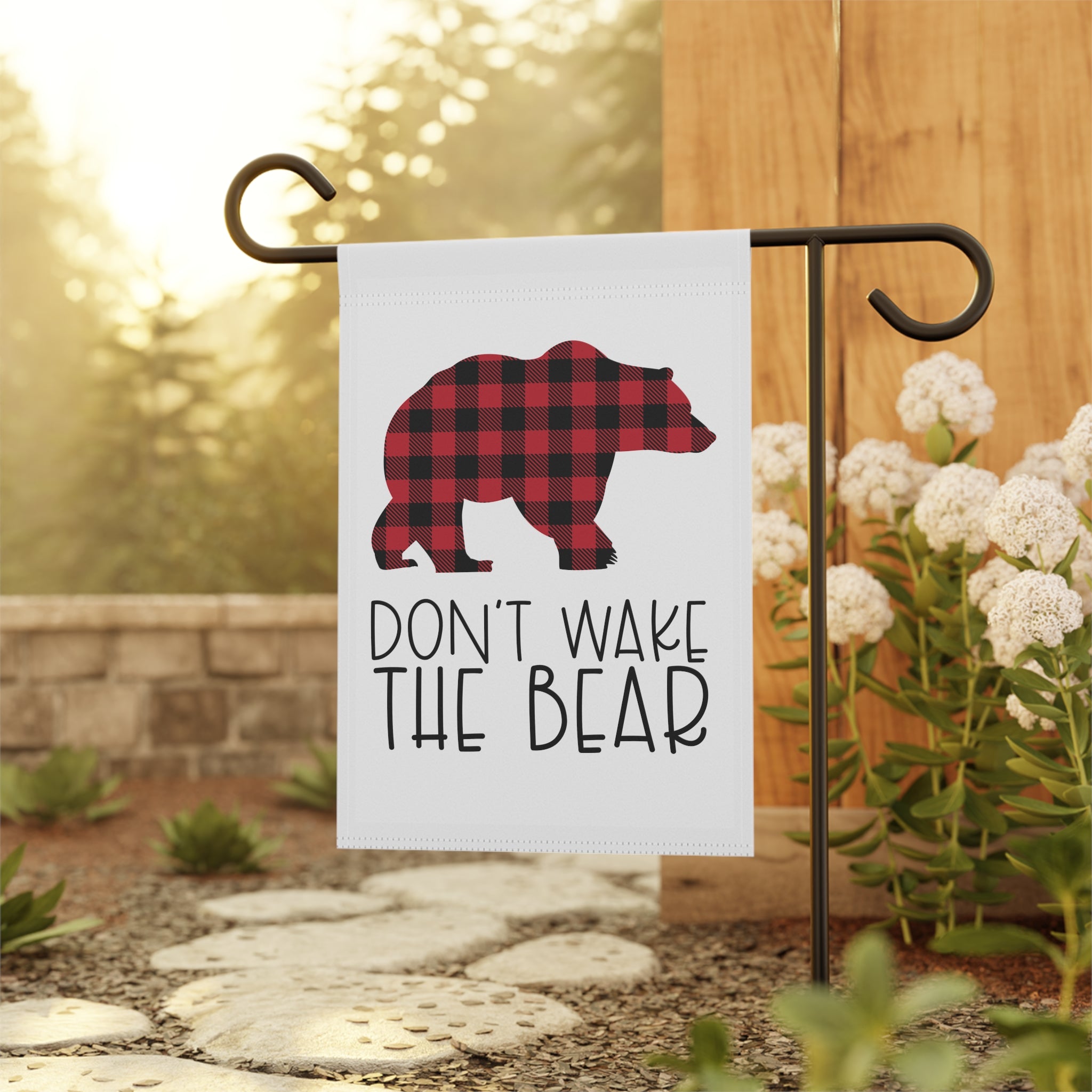 Buffalo plaid bear garden flag displayed outdoors on a cabin porch