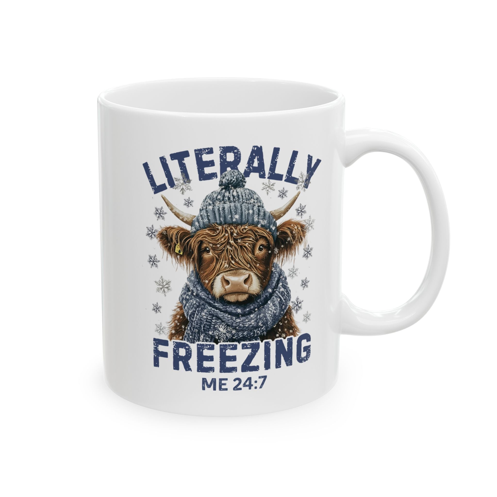 Mug with a highland cow wearing a hat and scarf, text 'Literally Freezing Me 24:7' on a white background
