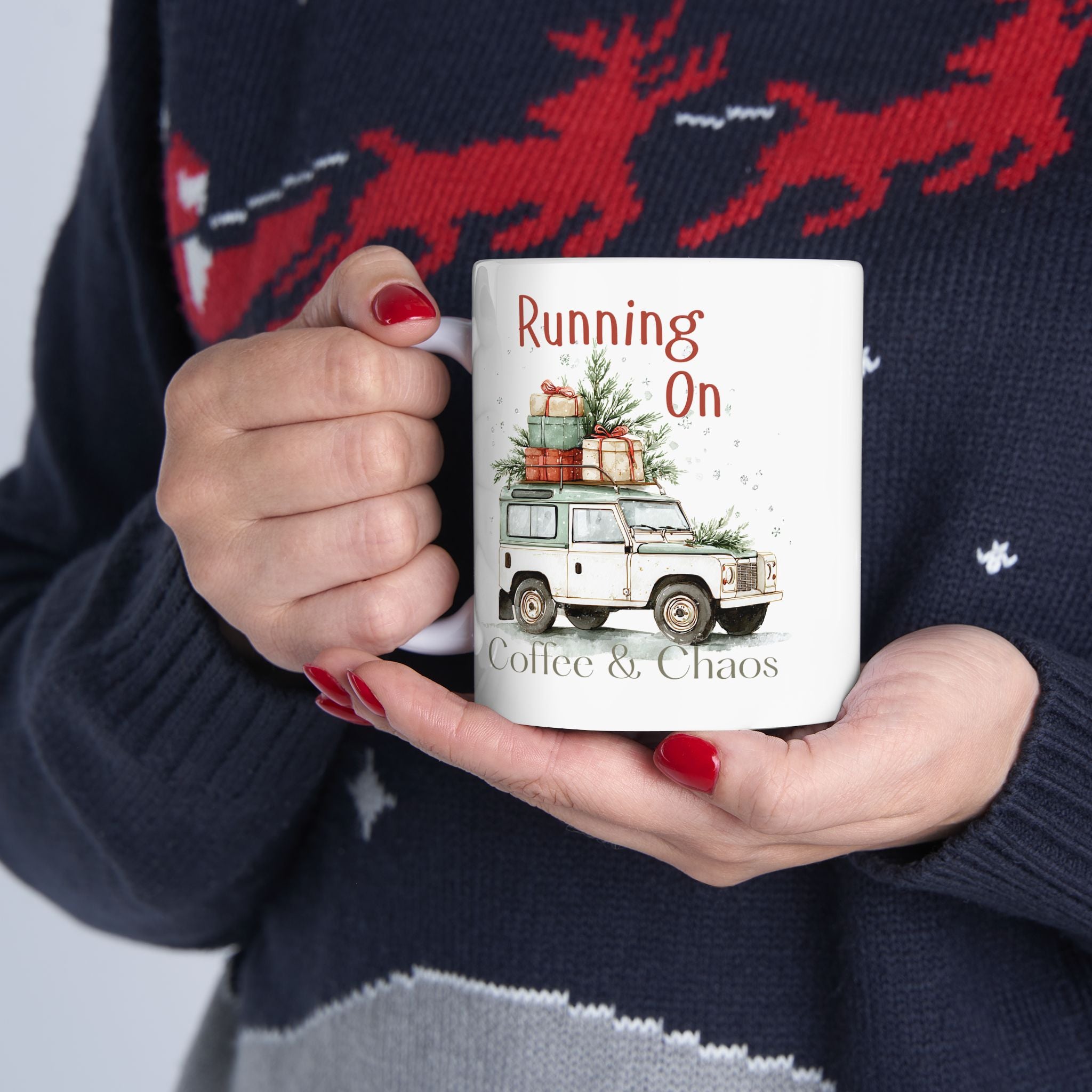 Person holding a mug with a Christmas-themed design and text, wearing a festive sweater.