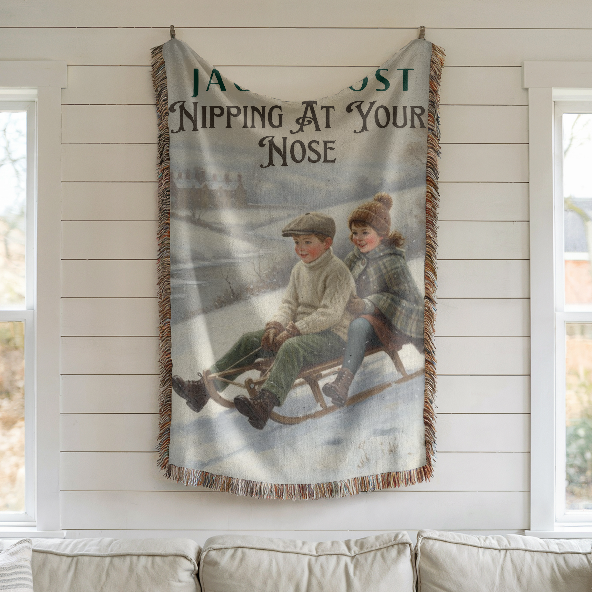 Woven blanket with vintage illustration of two children on a sled, hanging on a wall.