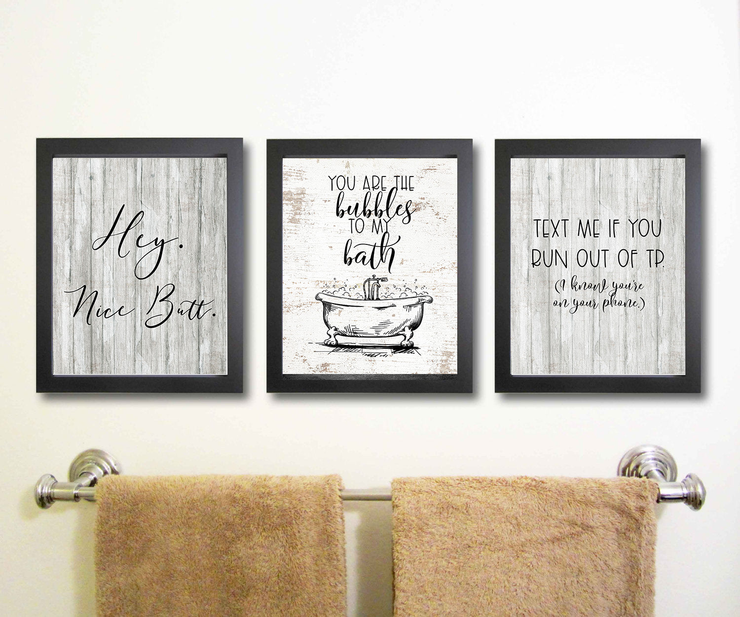 Three framed bathroom quotes on a wall above a towel rack.